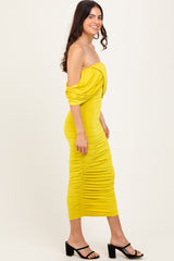woman wearing a yellow off-the-shoulder midi dress with ruched detailing and black heeled sandals