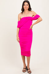 woman wearing a bright pink off-the-shoulder ruched midi dress and black strappy heels