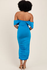 woman wearing a bright blue off-the-shoulder midi dress with ruched detailing from the back