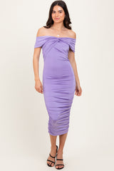 woman wearing a lavender off-the-shoulder ruched midi dress with a twist detail at the bust and a fitted silhouette