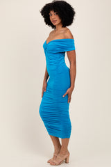 woman wearing a bright blue off-the-shoulder fitted dress with ruching detail and a bodycon silhouette
