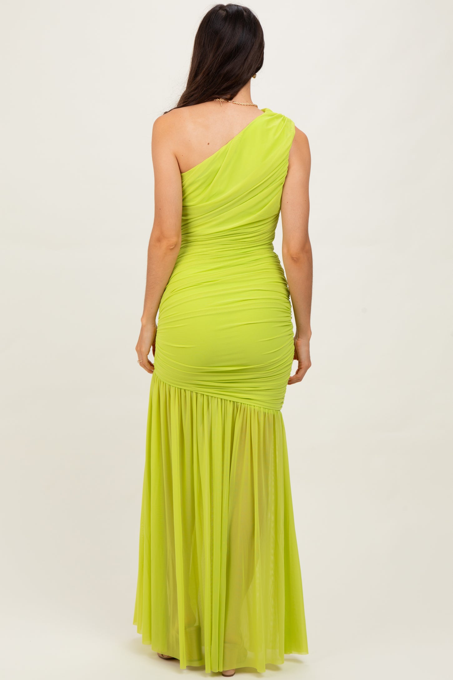 woman wearing a one-shoulder bright lime green evening gown with ruching and a flowy skirt