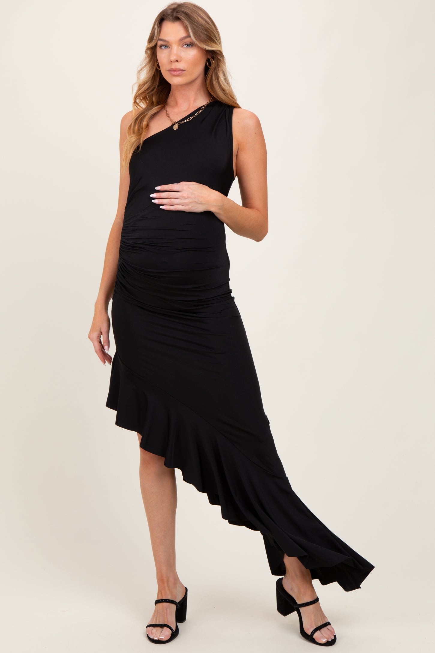 woman wearing a black one-shoulder maternity dress with ruffle detail and baby bump visible