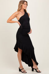 woman wearing a black one-shoulder maternity dress with a high-low hemline and holding her baby bump