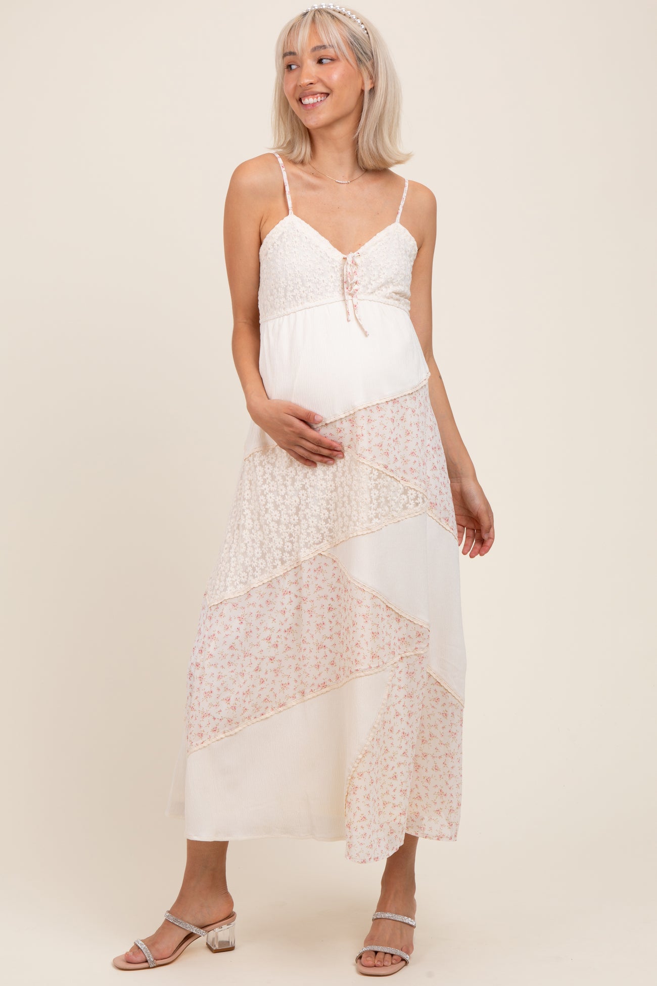 woman wearing a light pink and white tiered maternity dress with lace detailing and a baby bump visible