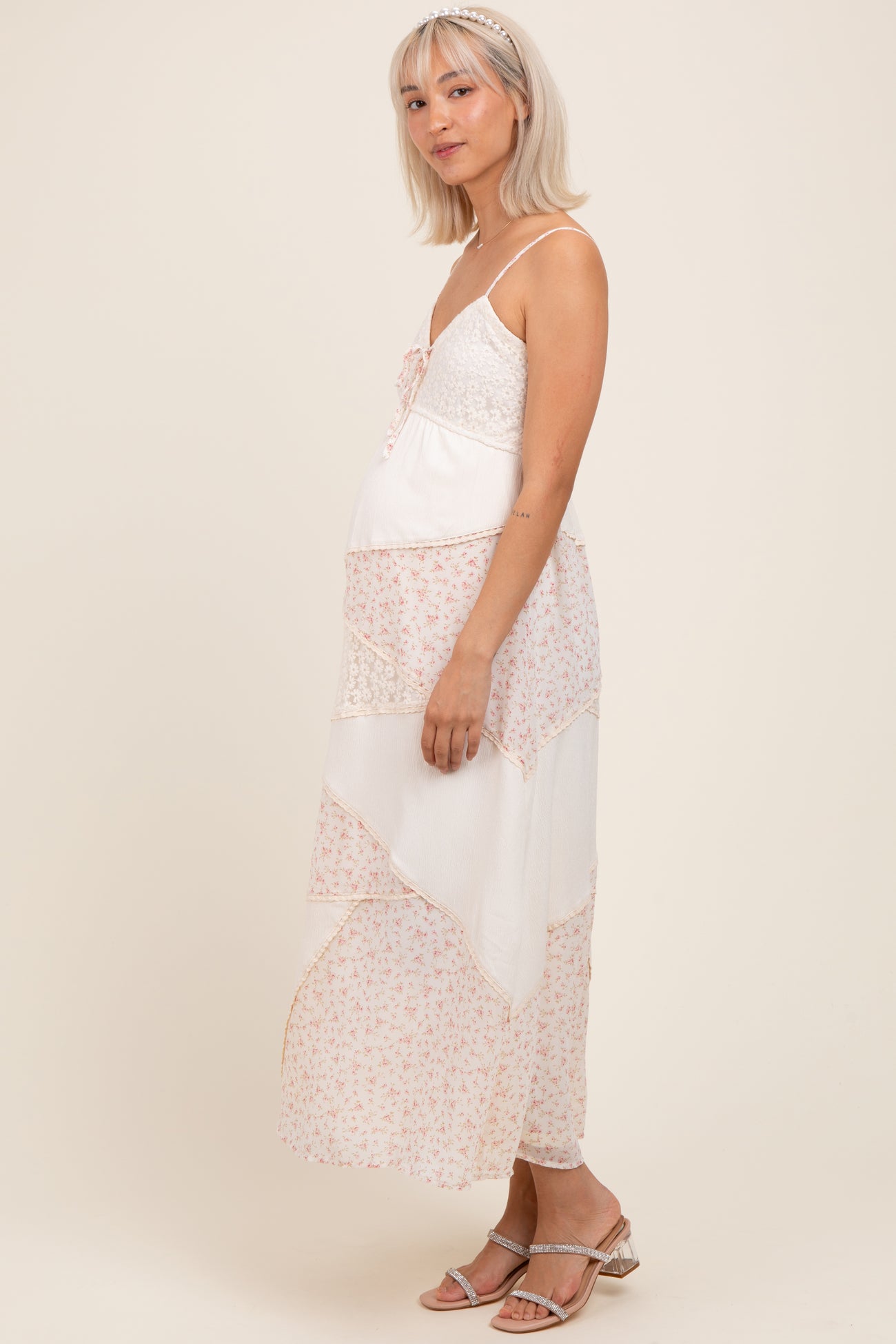 woman wearing a floral patterned maternity maxi dress with lace details and a visible baby bump