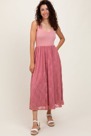 woman wearing a pink lace maxi dress with a fitted bodice and flared skirt, standing and smiling