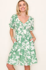 woman wearing a green floral print short sleeve dress with a v-neck and pockets