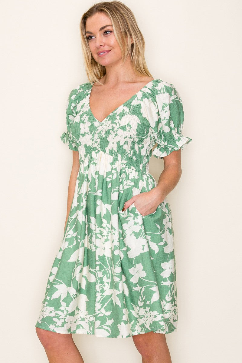 woman wearing a green floral print short sleeve dress with a v-neck and pockets