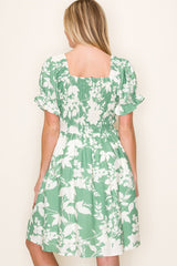 woman wearing a green floral print dress with a square neckline and puff sleeves, showing the back view