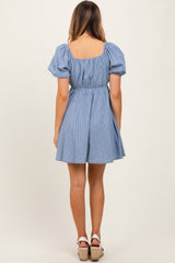 woman wearing a blue and white striped short dress with puff sleeves and a fitted waist, view from the back