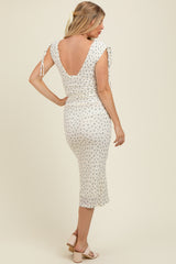 woman wearing a floral maternity dress with tie sleeves and a fitted silhouette, showcasing a low back