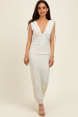 woman wearing a white floral print maxi dress with a deep V neckline and tie straps