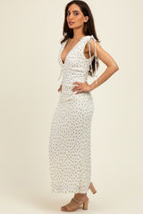 woman wearing a white floral maxi dress with tie straps and a deep v-neckline, standing sideways