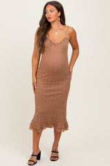 woman wearing a brown textured midi maternity dress with a ruffled hem and adjustable straps, showing her baby bump