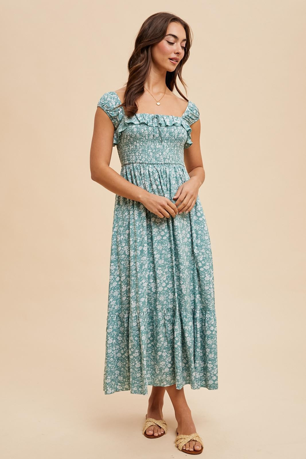 woman wearing a teal floral maxi dress with short ruffled sleeves and a fitted bodice