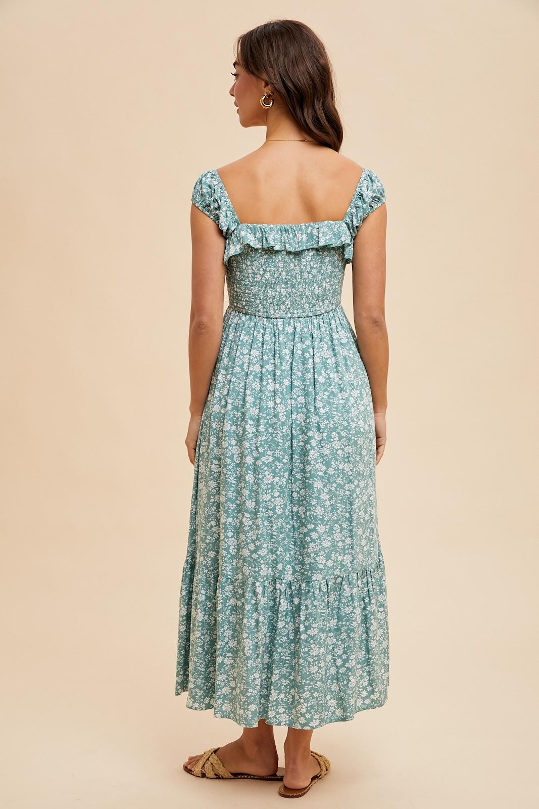 woman wearing a teal floral maxi dress with a smocked bodice and ruffled sleeves, shown from the back