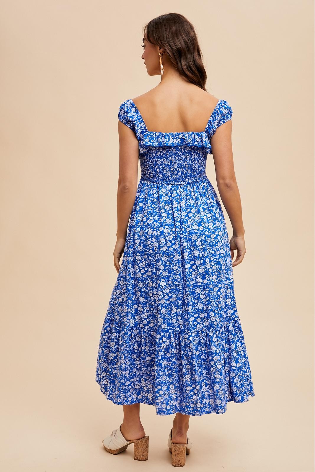 woman wearing a blue floral off-the-shoulder maxi dress with a smocked bodice and tiered skirt, showing the back view