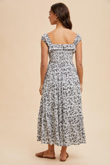 woman wearing a black and white floral maxi dress with a smocked back and ruffle straps, viewed from the back