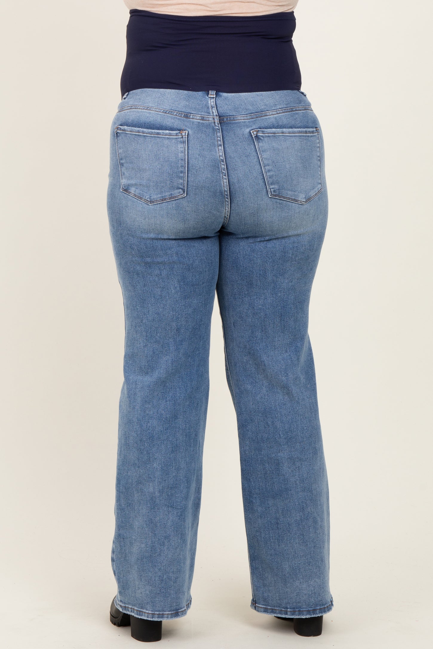 woman wearing a blue denim maternity plus jeans with a supportive waist panel, viewed from the back