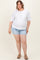 woman wearing a white short sleeve maternity top with a pocket and light blue denim shorts, showing her baby bump