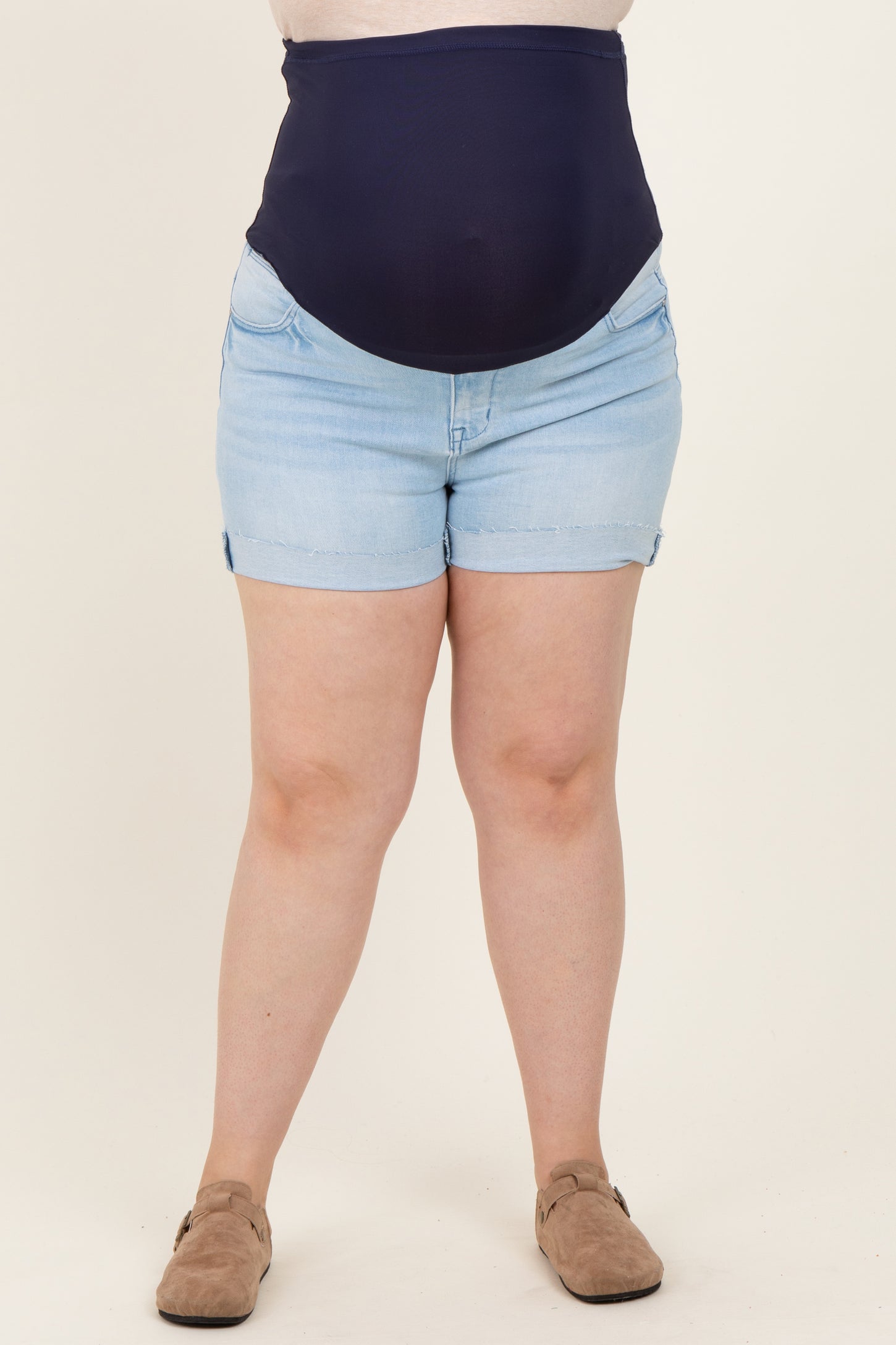 woman wearing a navy blue high-waisted maternity shorts with a visible baby bump