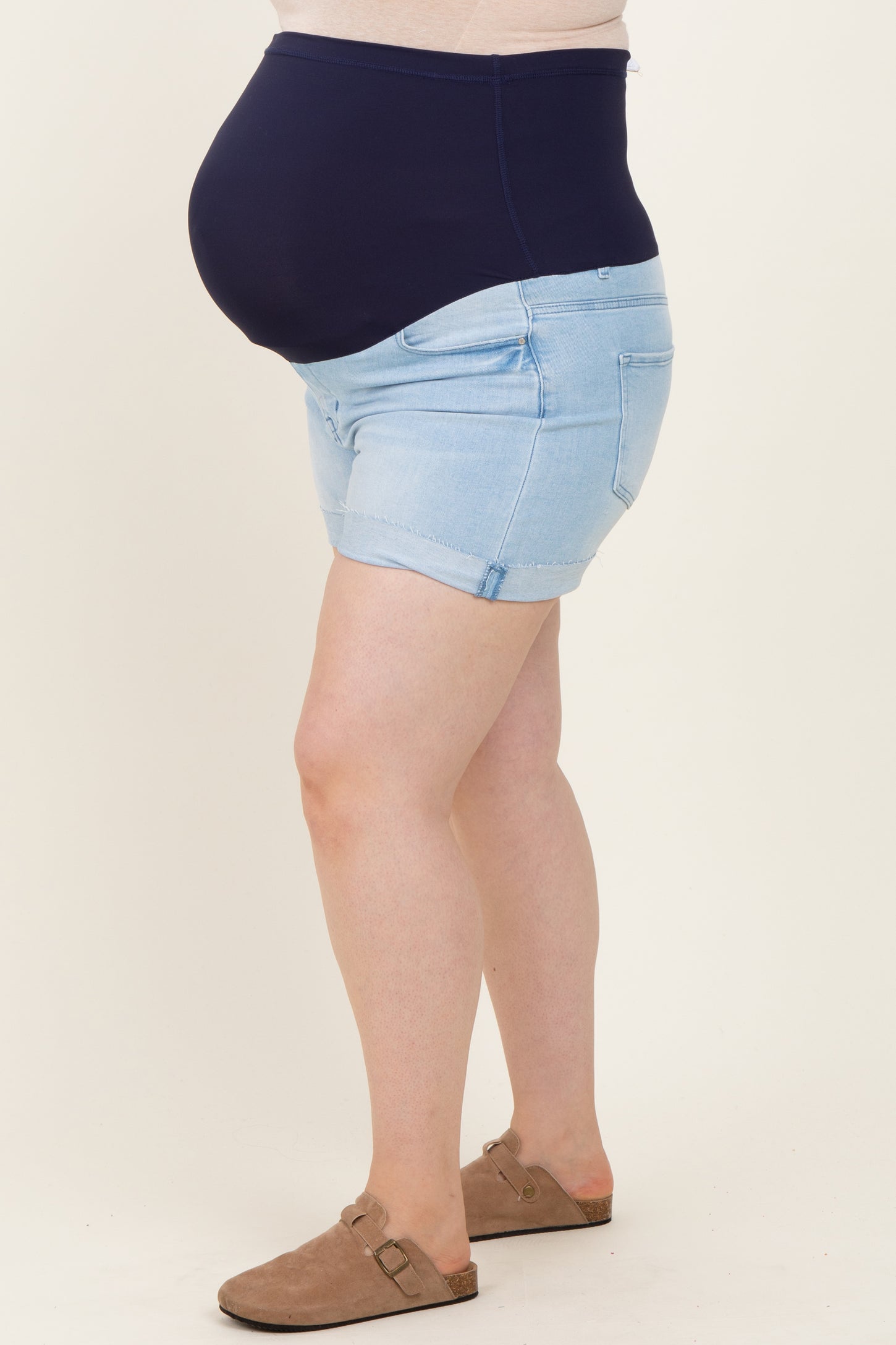 woman wearing maternity plus light blue denim shorts with a dark blue belly support band and a visible baby bump