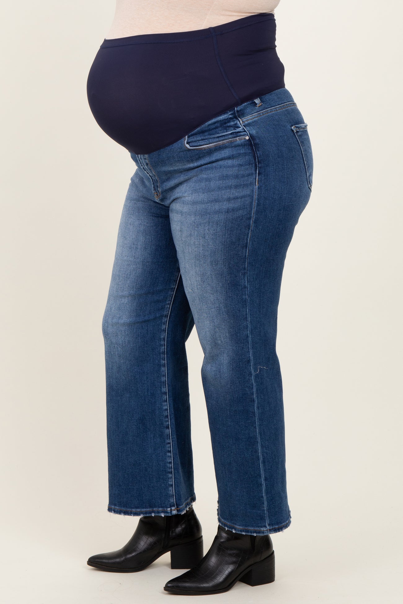 woman wearing dark blue maternity plus jeans with a stretchy waistband and a visible baby bump