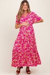 woman wearing a pink floral maxi dress with short sleeves and a button detail, showing her baby bump