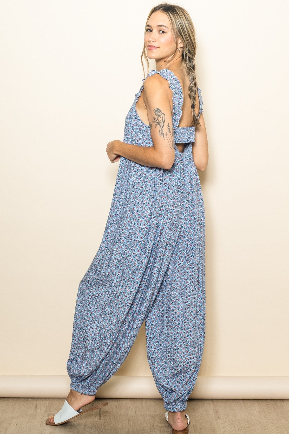 woman wearing a blue floral print jumpsuit with ruffle straps and loose harem style pants