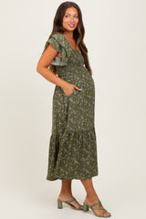 woman wearing a green floral print maternity dress with ruffled sleeves and pockets, highlighting her baby bump