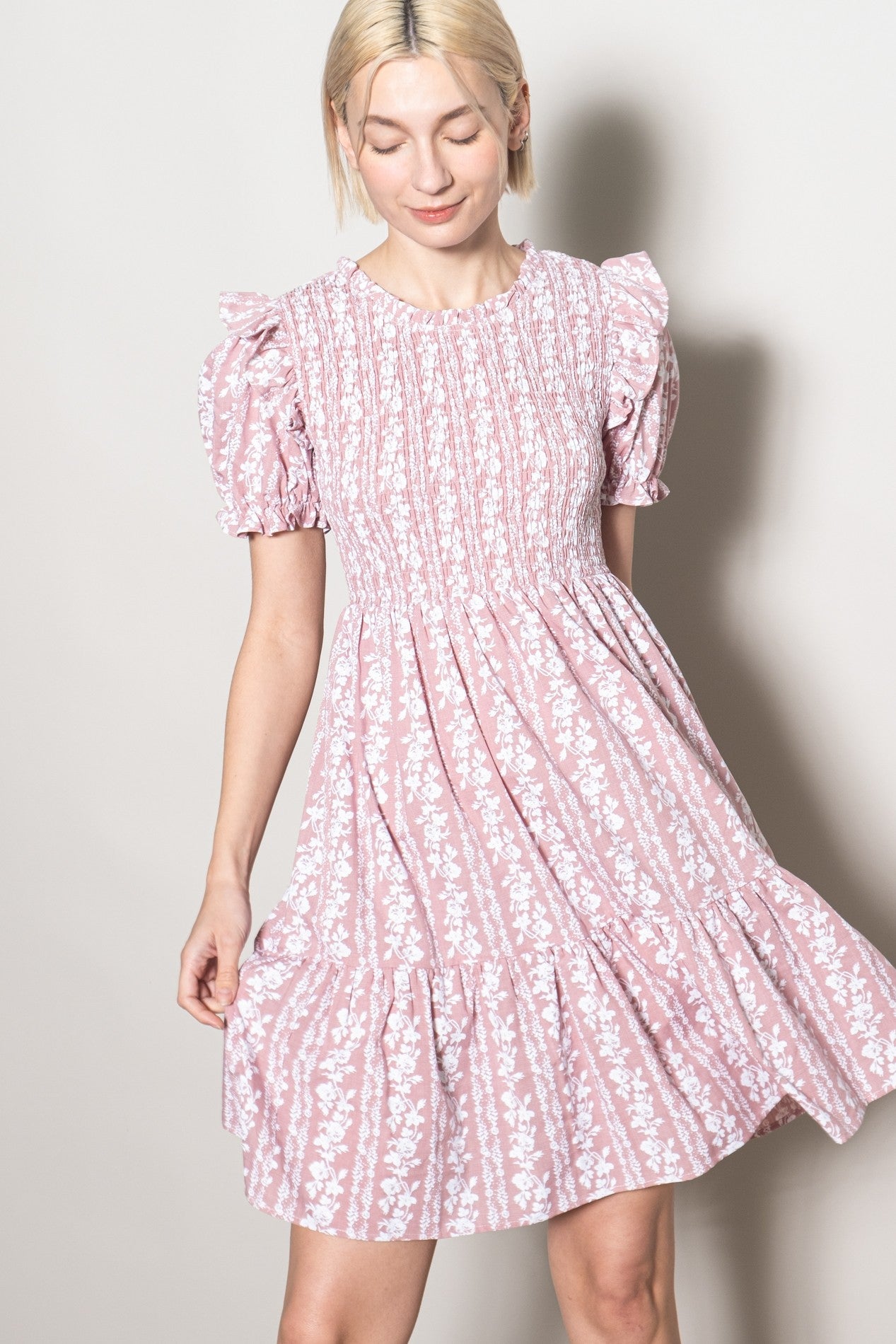 woman wearing a pink floral short sleeve dress with smocked bodice and ruffled sleeves