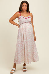 woman wearing a floral maternity maxi dress with a fitted bodice and flowing skirt, showcasing her baby bump
