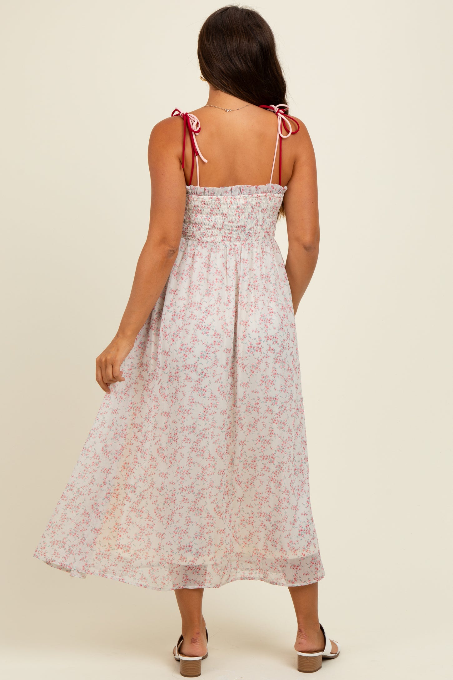 woman wearing a floral maternity maxi dress with tie shoulder straps and a smocked bodice, showing a baby bump