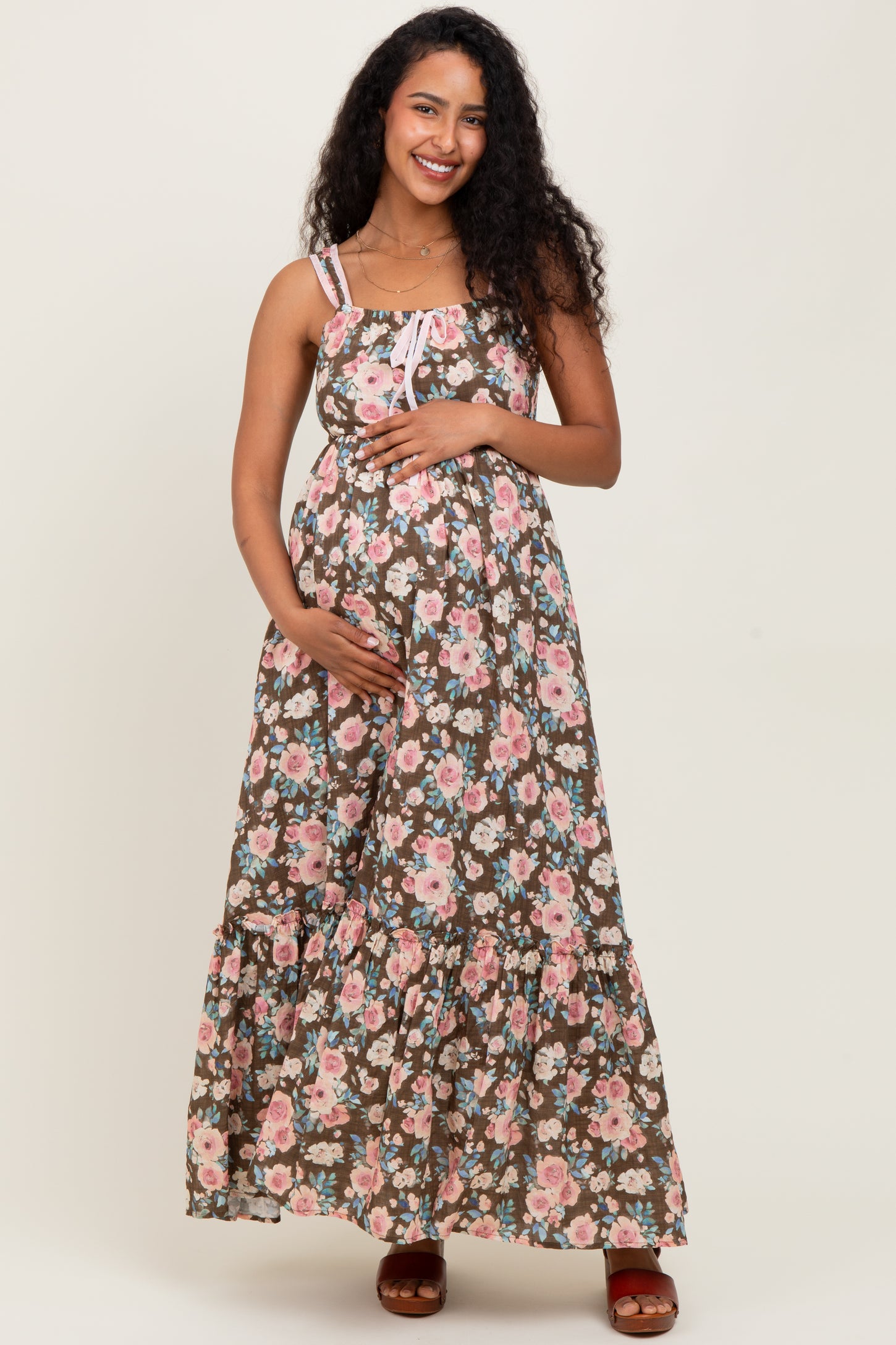 woman wearing a brown floral maternity maxi dress and holding her baby bump
