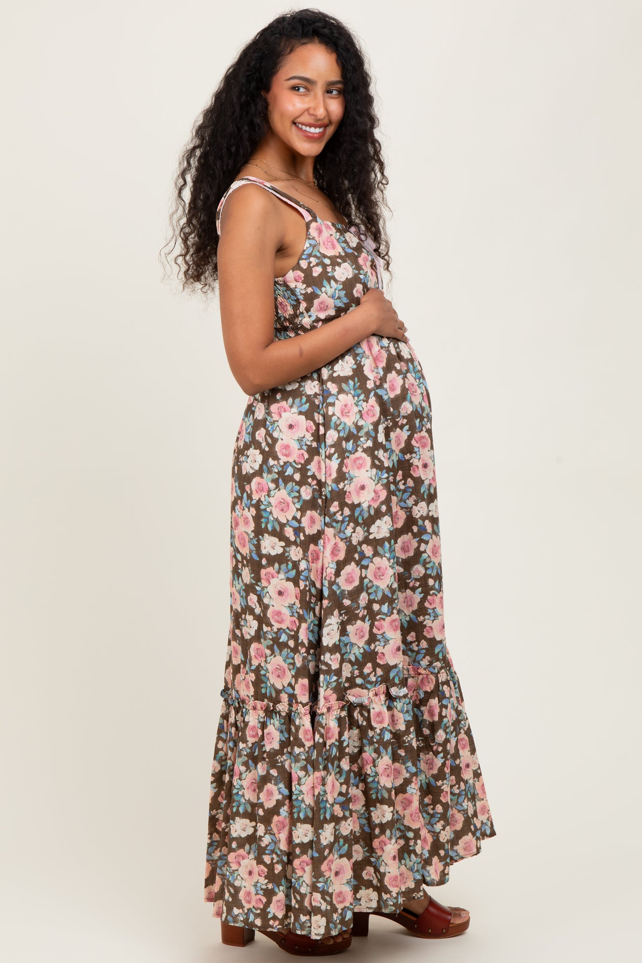 woman wearing a brown floral print maternity maxi dress and holding her baby bump