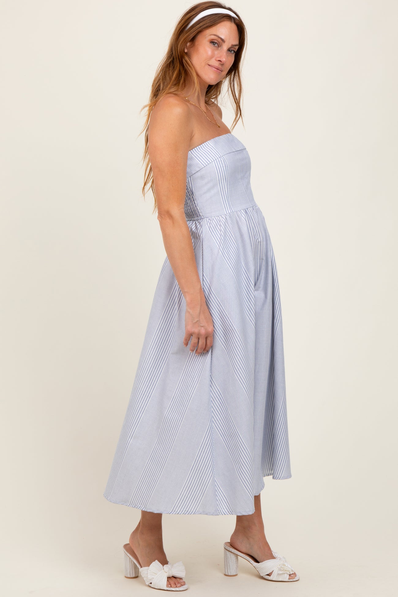 woman wearing a blue and white striped strapless midi dress with a fitted bodice and full skirt