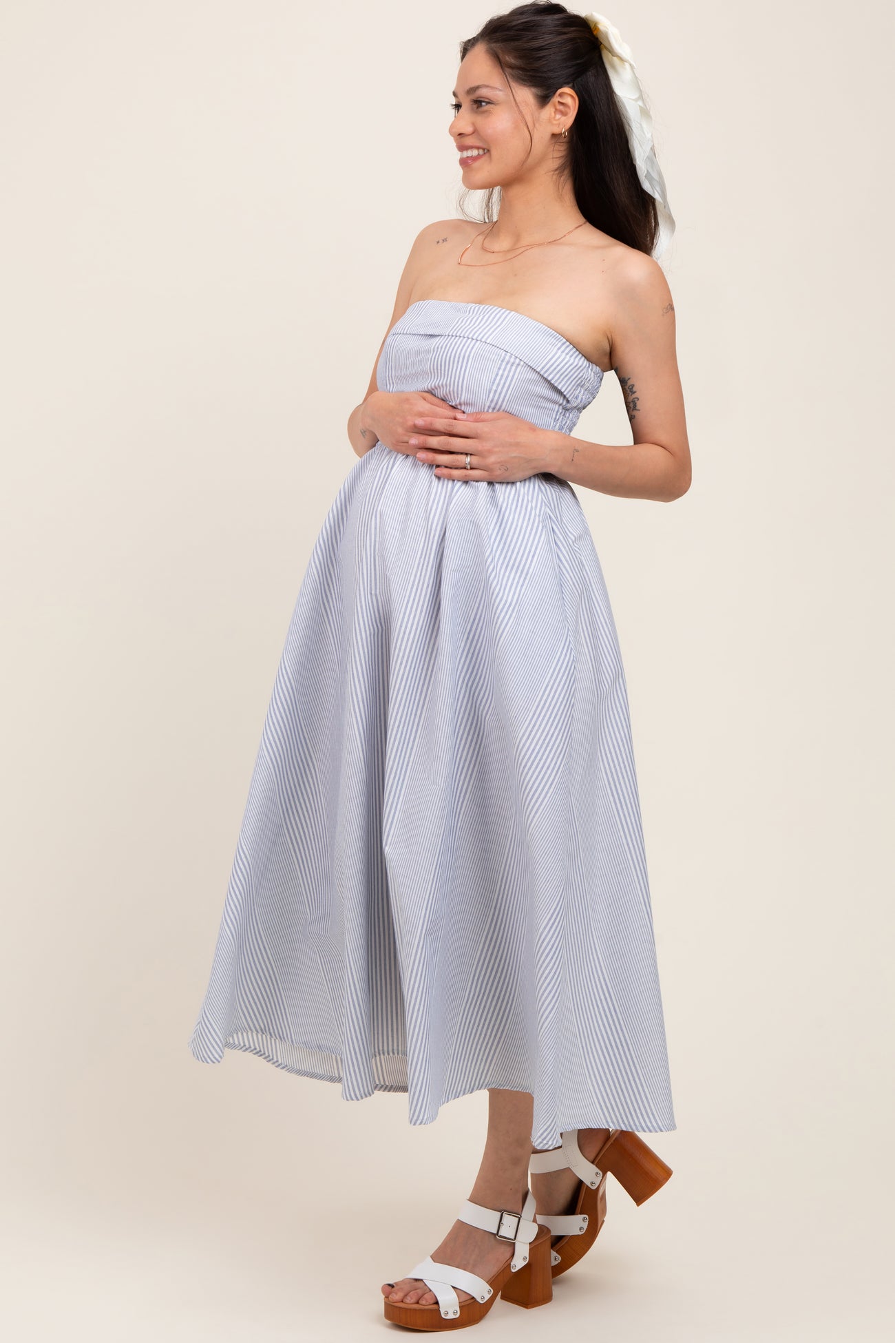 woman wearing a strapless blue and white striped maternity dress with a visible baby bump