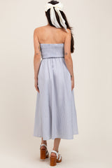 woman wearing a blue and white striped maternity dress with a smocked bodice and a flowy skirt from the back.