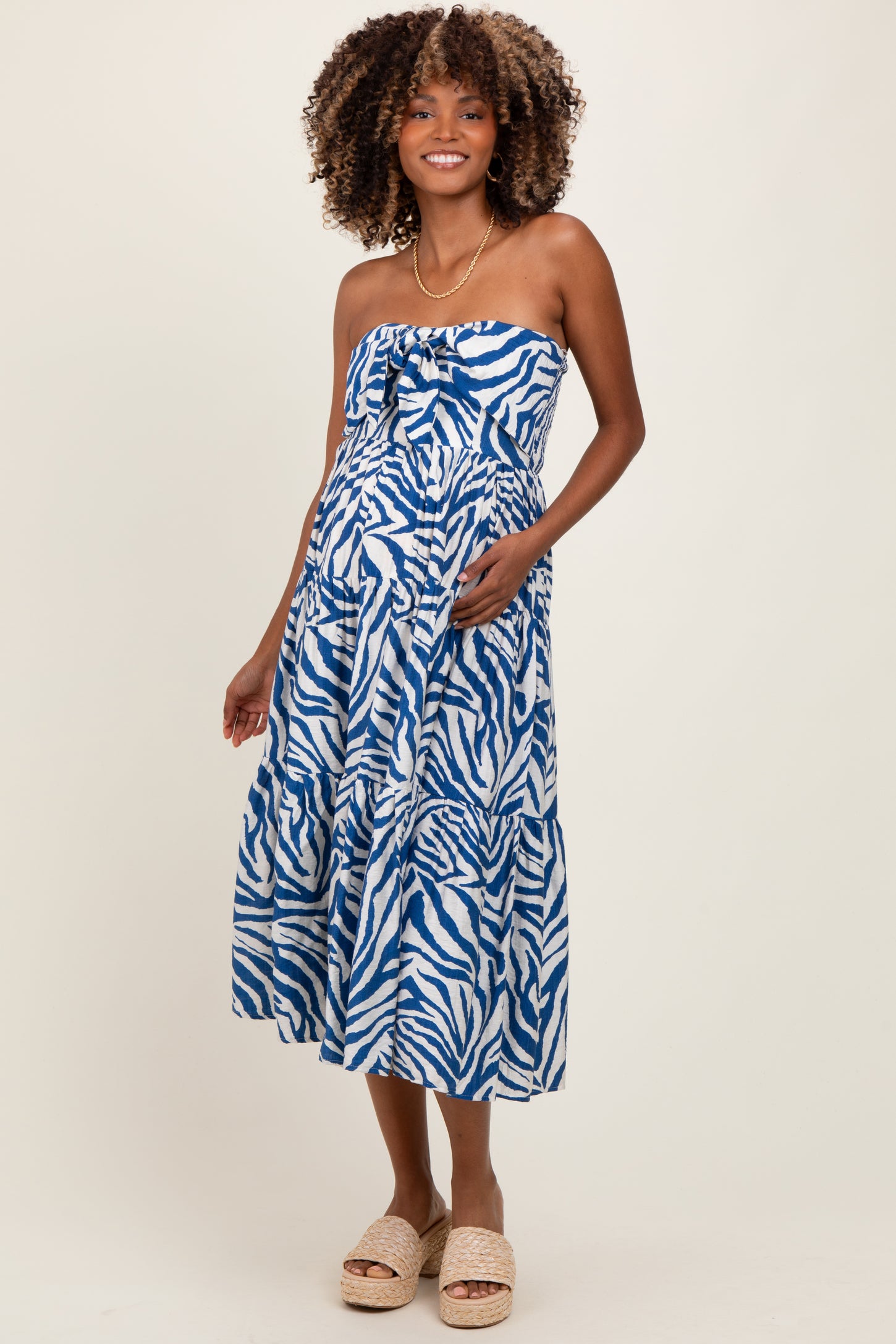woman wearing a blue and white zebra print maternity dress with a bow and a baby bump visible