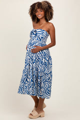 woman wearing a blue and white zebra print maternity dress with a fitted bodice and a flowing skirt, showing her baby bump