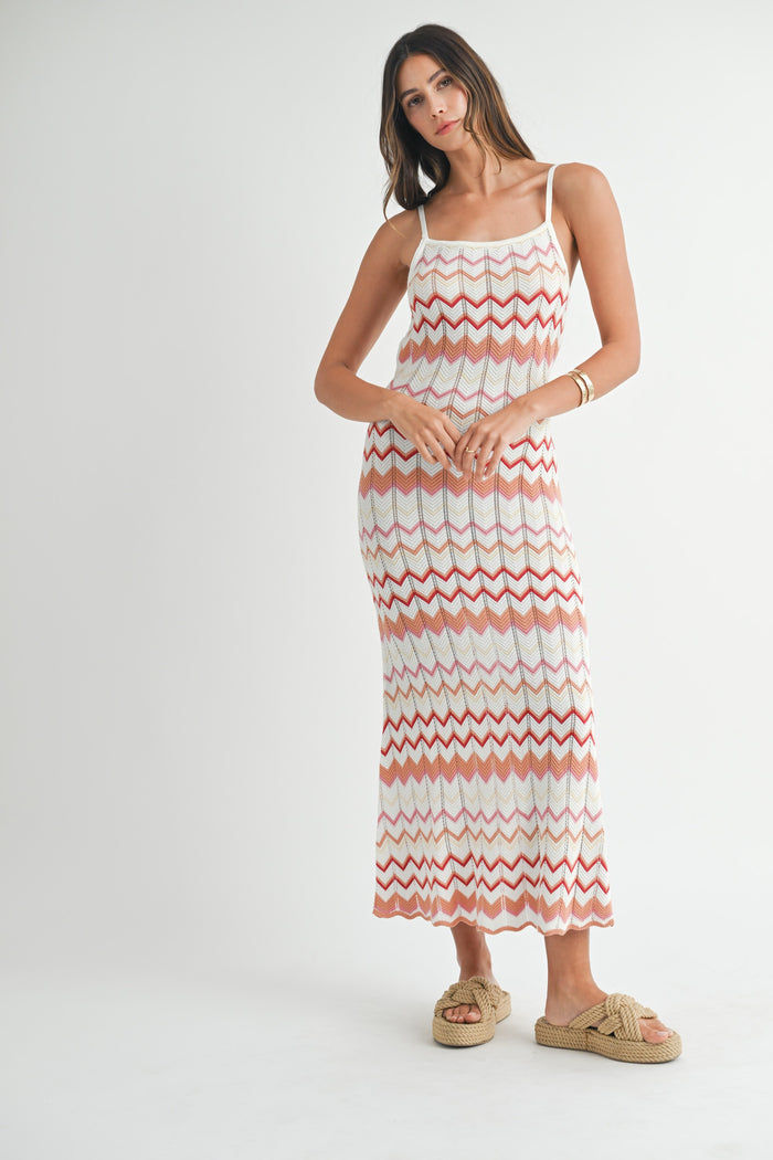 woman wearing a white and coral zigzag patterned maxi dress with spaghetti straps and tan slide sandals