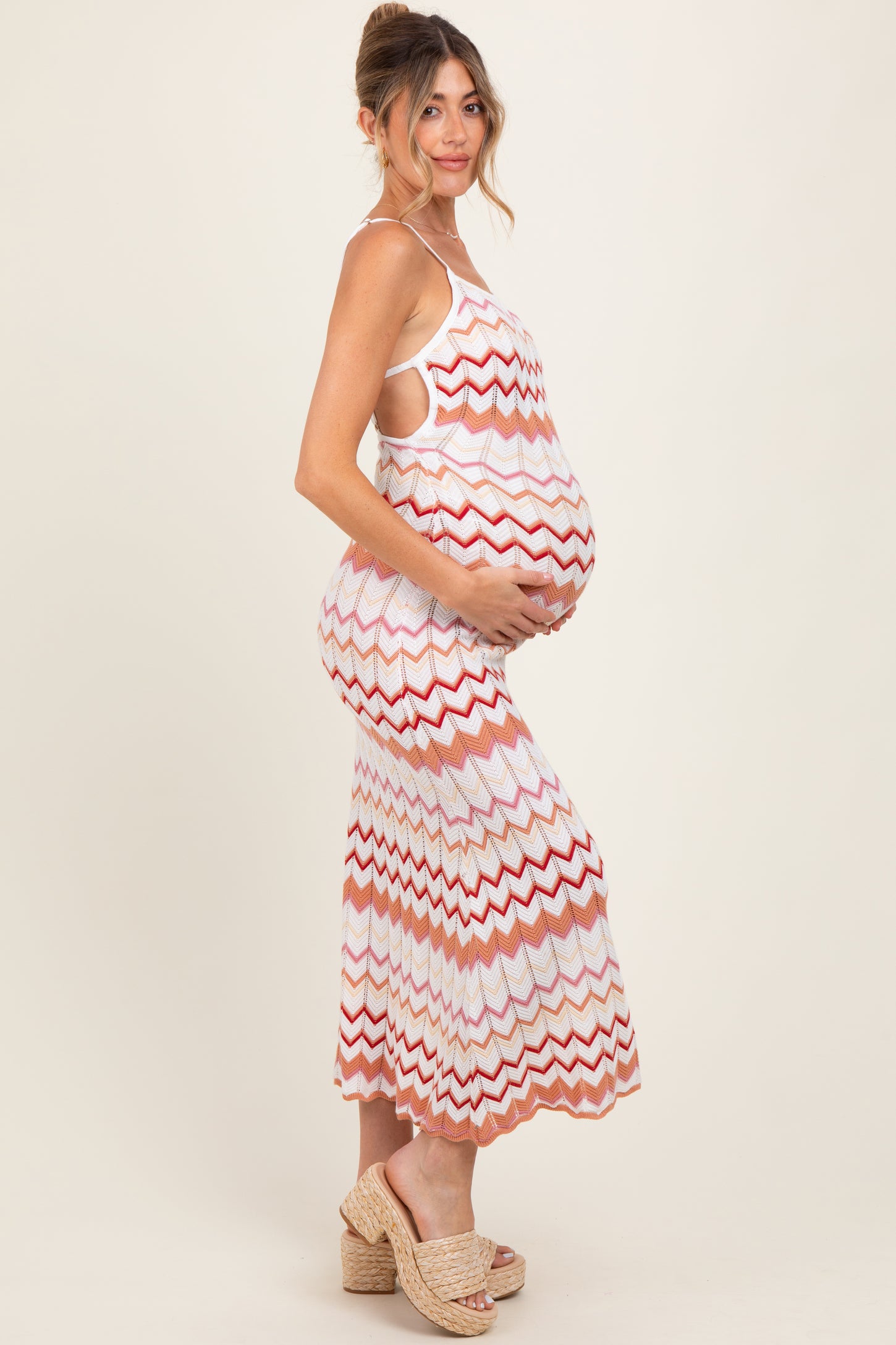 woman wearing a multicolored zigzag patterned maternity dress, showing her baby bump