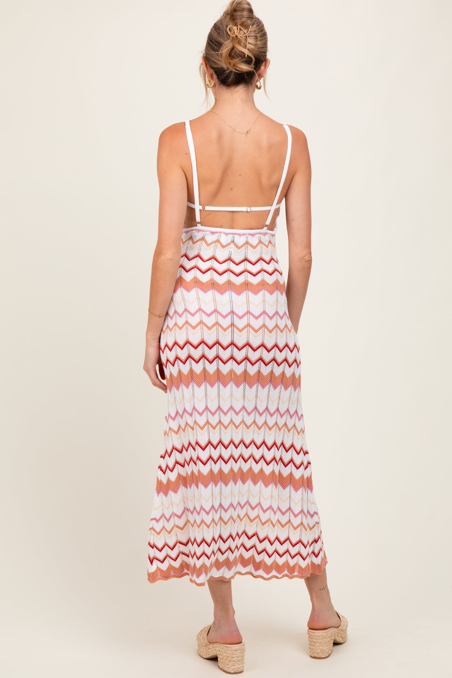 woman wearing a maternity zigzag patterned maxi dress with a strappy back, showing a baby bump