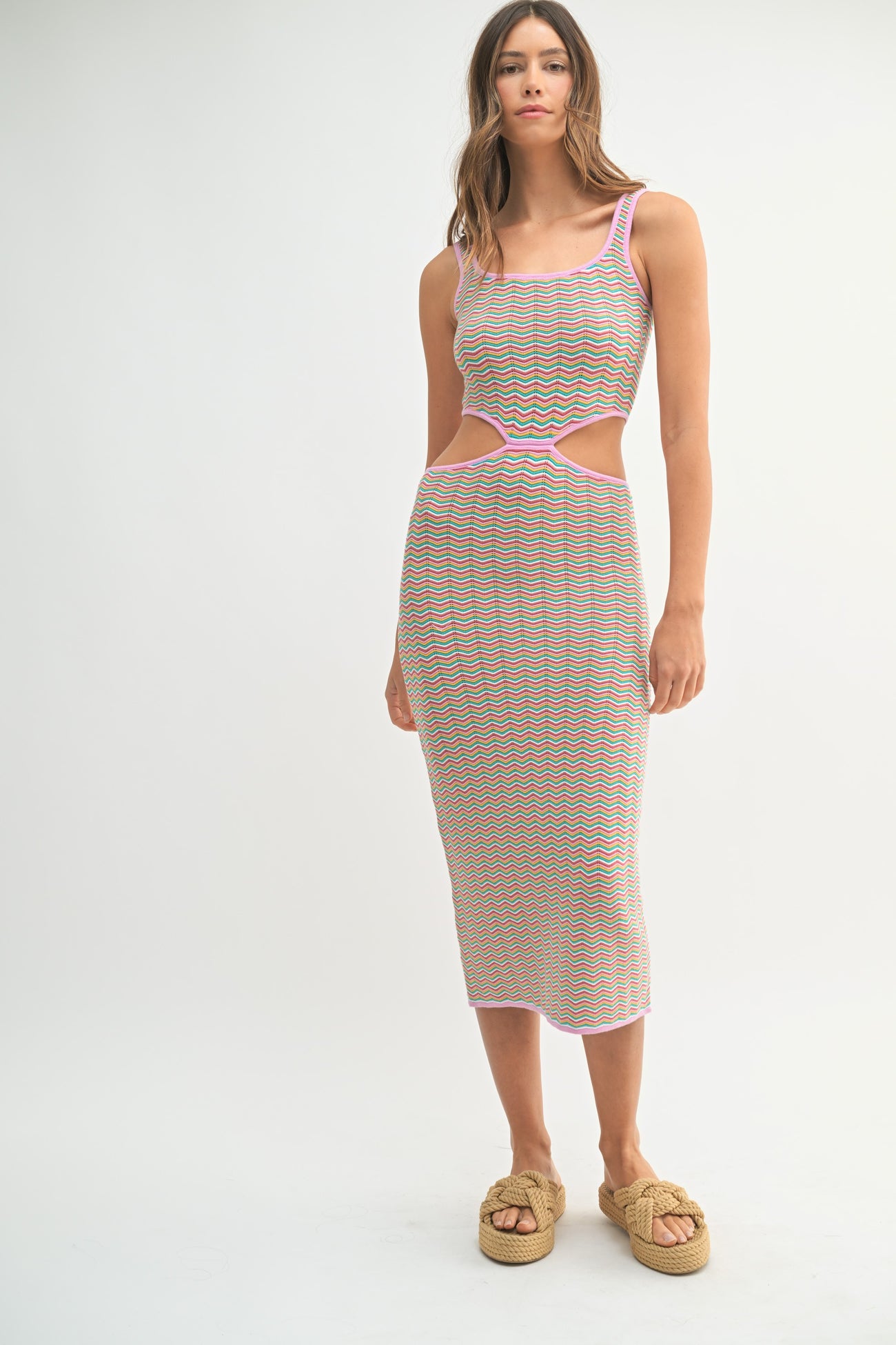 woman wearing a multicolored striped midi dress with cut-out details and pink trim, styled with woven platform sandals