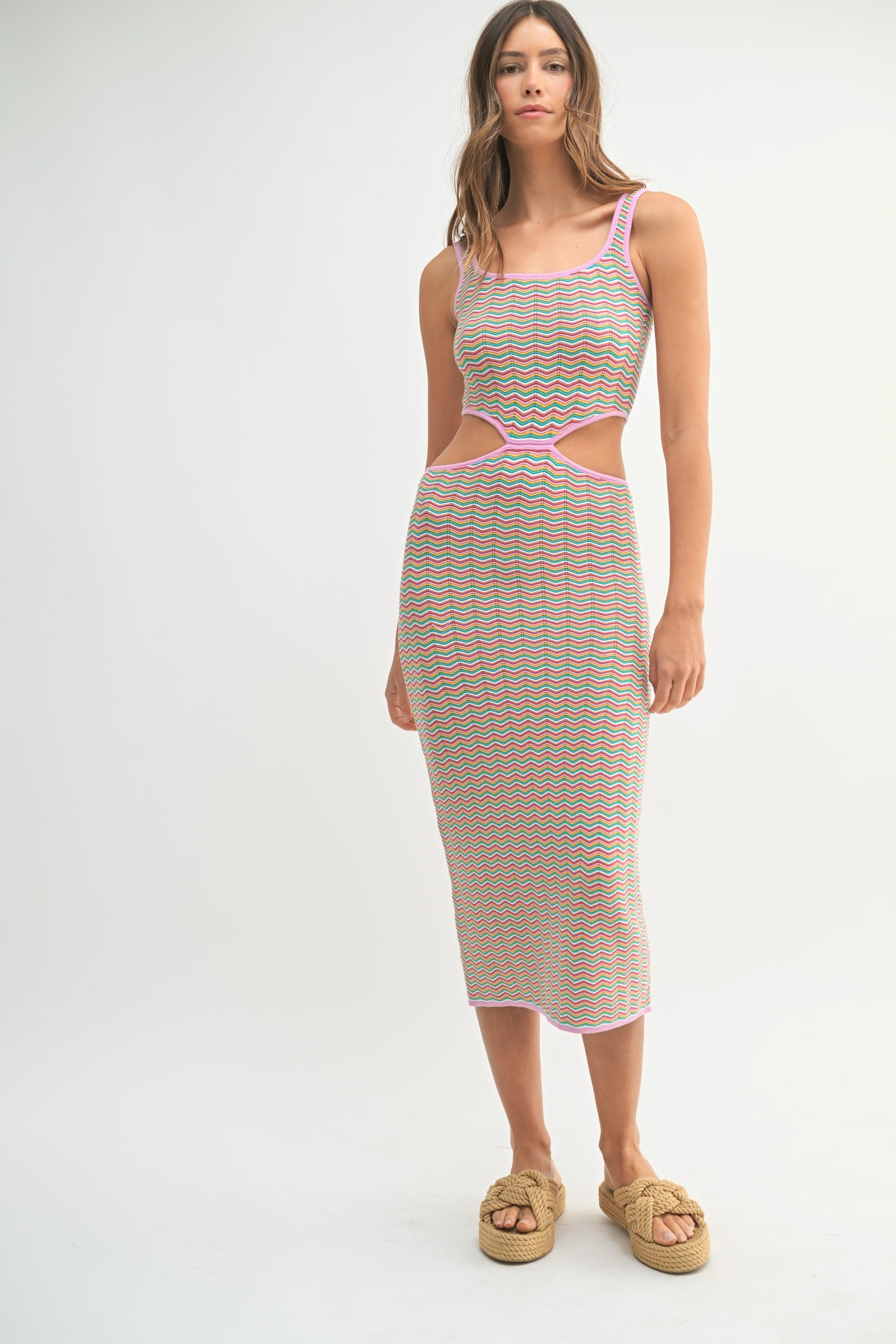 woman wearing a multicolored striped midi dress with cut-out details and pink trim, styled with woven platform sandals
