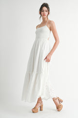 woman wearing a white maxi dress with a smocked bodice and eyelet detailing, paired with brown platform heels