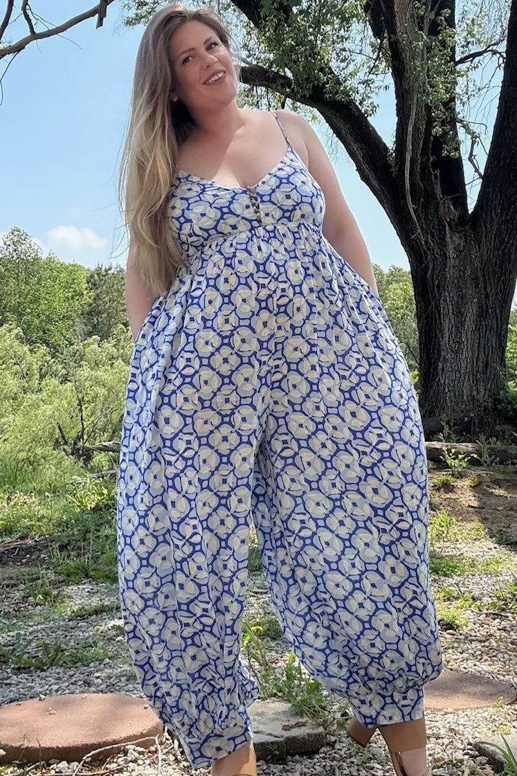 woman wearing a blue and white floral maternity jumpsuit with a relaxed fit and spaghetti straps