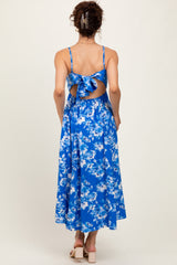 woman wearing a blue floral midi dress with a back tie detail and open back, showing a flowy skirt