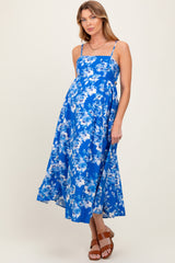 woman wearing a blue floral maternity dress with a fitted bodice and flowing skirt, displaying a baby bump